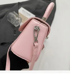 Dettaglio borsa a mano rosa cipria con fibbie in metallo argento e tracolla elegante