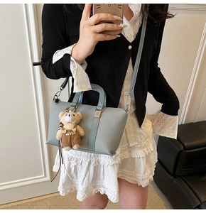 Detail of light blue woven bucket bag featuring a cute teddy bear charm and strap