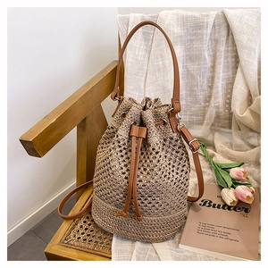 Detailed view of woven straw bucket bag with drawstring closure and brown leather straps