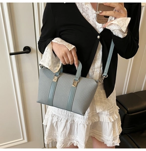 Detailed view of woven texture and silver hardware on a light blue-grey bucket bag