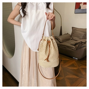Detail of cream woven bucket bag with brown leather drawstring and thin shoulder strap