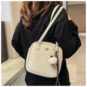 Detail of cream square shoulder bag with plush ice cream charm and metal logo lettering