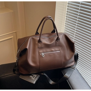 Détail macro du sac de voyage en cuir marron foncé avec poignées renforcées et boucles métal