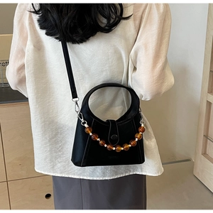 Detail of a black leather bucket bag with amber gradient beads and silver metal hooks