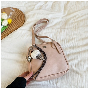 Detail of nude pink square shoulder bag with ice cream charm and metal logo on fabric