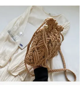 Detail of hand-woven drawstring straw bucket bag with wooden beads and knit strap