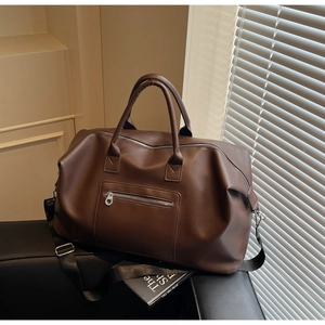 Sac de voyage marron foncé en similicuir avec poche zippée dans un décor épuré
