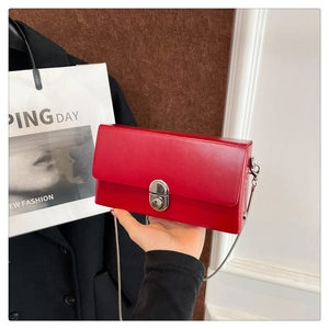 Macro shot of stylish red leather box bag featuring a silver twist lock and metal chain strap