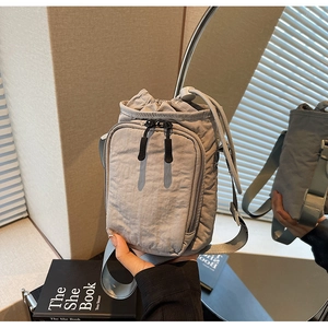 Detailsicht der grauen Kordelzug-Flaschentasche mit plissiertem Nylon und Reißverschlusstasche