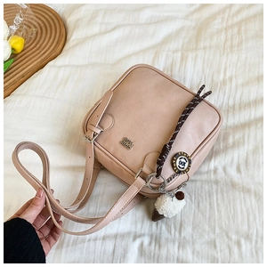 Close-up of pink square underarm bag with plush ice cream charm and metal logo