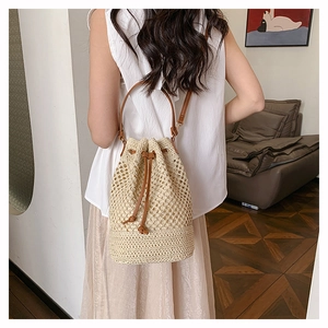Detail of hand-woven beige bucket bag with brown leather drawstring and mesh texture