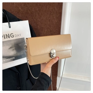 Detail of milk tea leather crossbody bag with silver rotating clasp and chain strap