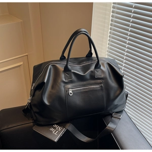 Détail du sac de voyage en similicuir noir avec texture souple et doubles poignées