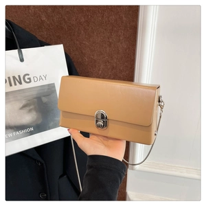 Detail of khaki crossbody box bag featuring silver metal lock and sleek chain strap