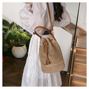 Close-up of lightweight woven hollow bucket bag with leather straps and drawstring closure