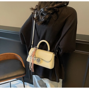 Detail van crèmewitte crossbodytas met zilveren sluiting en decoratieve zijden sjaal