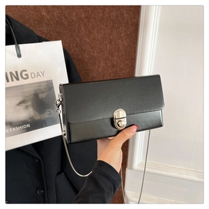 Detail of black box bag with silver metal swivel lock and slender chain strap
