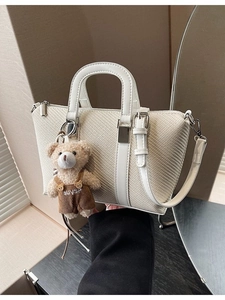 Chic cream woven bucket bag with leather handles and a cute bear charm pendant
