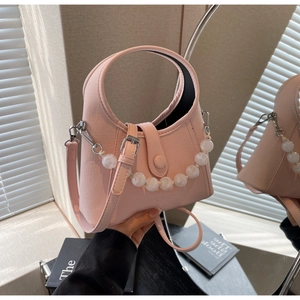 Close-up of pink leather bucket bag featuring a large faux pearl chain and handle
