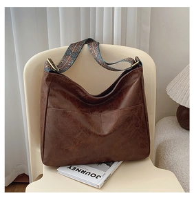 Close-up of vintage brown tote bag with geometric ethnic weave strap on ivory chair