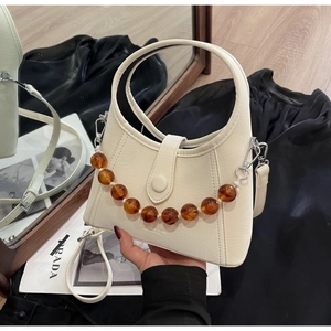 Detail of cream white beaded bucket bag with amber chain and smooth leather texture