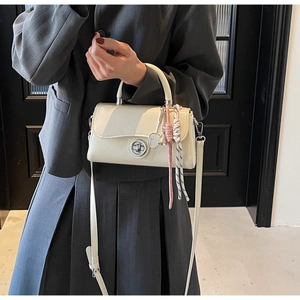 Detail van gebroken witte crossbodytas met tennisracket hanger en metalen sluiting