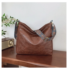 Close-up of retro brown tote bag featuring wide colorful geometric patterned shoulder strap