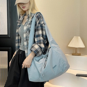 Detail of light blue waterproof nylon shoulder bag featuring drawstring closure and wide strap