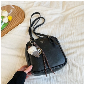 Detail of black leather square bag with silver logo and cute ice cream plush charm