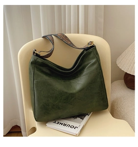 Detail of dark green leather tote bag with ethnic embroidery wide strap and gold hardware