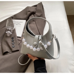 Detailed shot of sage green bucket bag with white bead chain and circular handle
