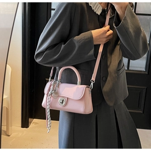 Roze crossbodytas met een zilveren draaisluiting en een gestreepte zijden sjaal accessoire
