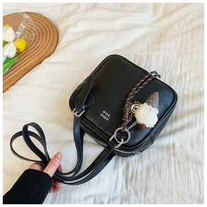 Detail of black square shoulder bag with plush ice cream charm and white typography