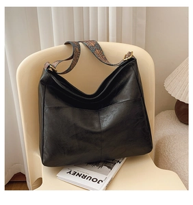 Detail of vintage black hobo bag showing its leather texture and colorful jacquard strap