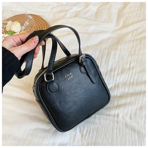 Close-up of black PU leather square bag with gold COIH V2DN logo and zipper detail