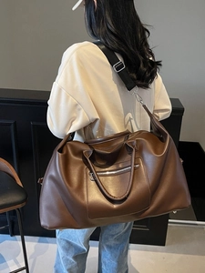 Grand sac de voyage en cuir marron foncé avec bandoulière porté par un mannequin