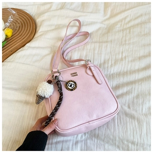 Detailed view of a pink small square shoulder bag with cute charms and a tulip accessory