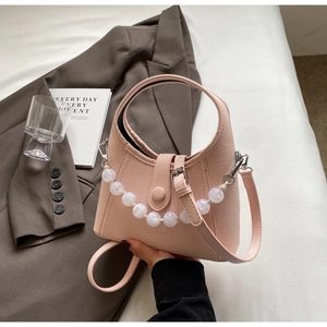 Detailed view of light pink beaded handbag with white pearl strap and buckle closure