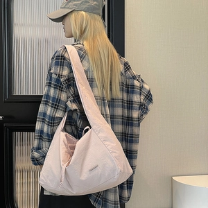 Close-up of light pink nylon tote bag with drawstring detail on female model's shoulder