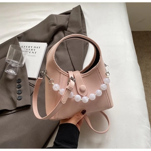 Detail of pink pebbled leather bucket bag with white pearl chain and branded logo