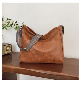 Detail of vintage brown tote bag featuring ethnic style wide strap and leather texture