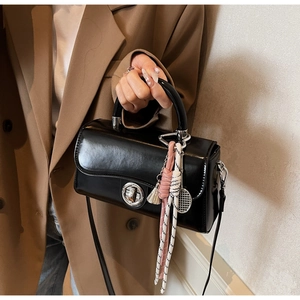 Detail van zwarte laklederen crossbody tas met zilveren sluiting en kleurrijke kwast