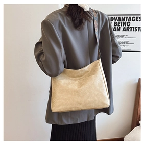 Close-up of beige tote bag with a retro ethnic pattern wide strap on model's shoulder