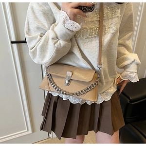 Detail of light beige crossbody bag with silver chain and metallic twist-lock closure