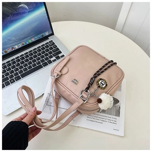 Detailed view of a pink square shoulder bag featuring a cute ice cream plush charm