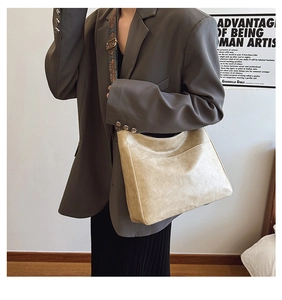 Close-up of beige glossy PU leather tote with a retro jacquard wide shoulder strap