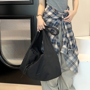 Close-up of black nylon tote bag with drawstring closure and wide shoulder strap