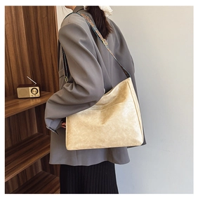 Detail of cross-stitched beige leather tote bag with vintage patterned wide strap