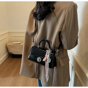 Detail van een glanzende zwarte lederen crossbody tas met roze koord en zilveren sluiting