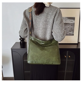 Close-up of a retro green tote bag featuring a wide bohemian embroidered shoulder strap